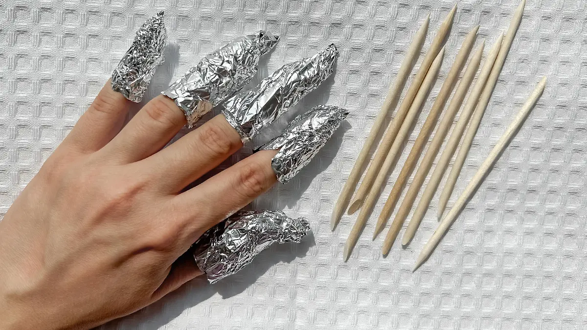 The process of removing gel polish from nails. Nails wrapped in foil on a white towel.
