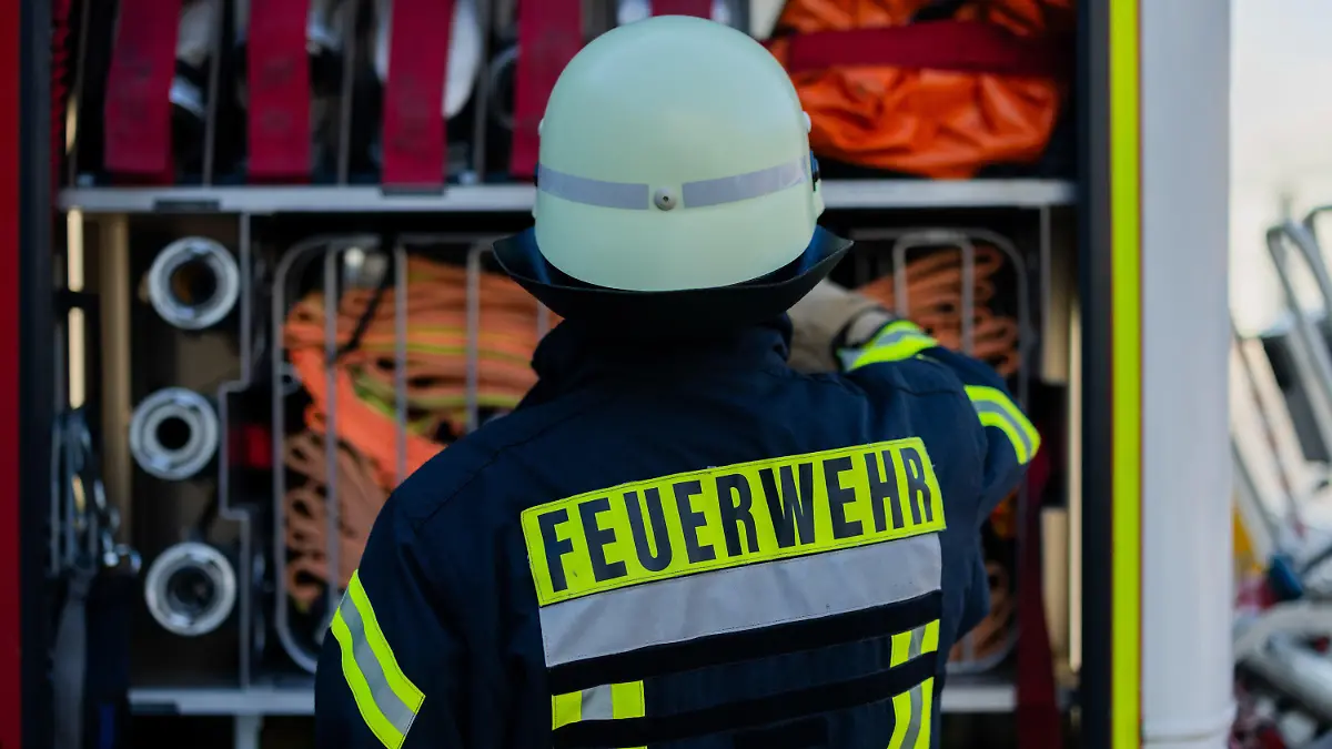 ARCHIV - 11.01.2024, Nordrhein-Westfalen, Leverkusen: Ein Feuerwehrmann holt Equipment aus einem Einsatzfahrzeug an der Feuerwache der Feuerwehr. (zu dpa: «Brand auf Balkon: Mehr als 100 Menschen aus Hochhaus evakuiert») Foto: Rolf Vennenbernd/dpa +++ dpa-Bildfunk +++