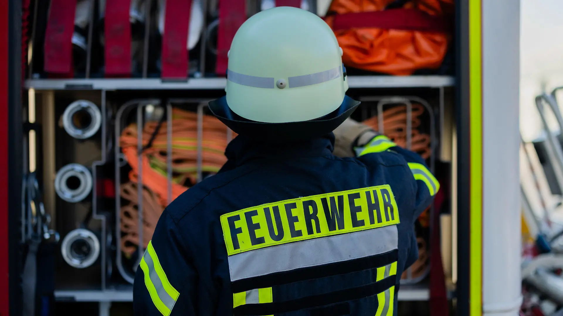 ARCHIV - 11.01.2024, Nordrhein-Westfalen, Leverkusen: Ein Feuerwehrmann holt Equipment aus einem Einsatzfahrzeug an der Feuerwache der Feuerwehr. (zu dpa: «Brand auf Balkon: Mehr als 100 Menschen aus Hochhaus evakuiert») Foto: Rolf Vennenbernd/dpa +++ dpa-Bildfunk +++