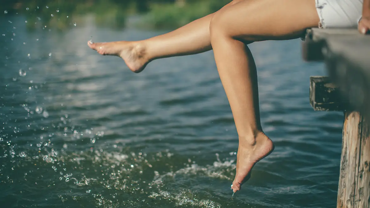 Young woman splashing water with beautiful legs at lake