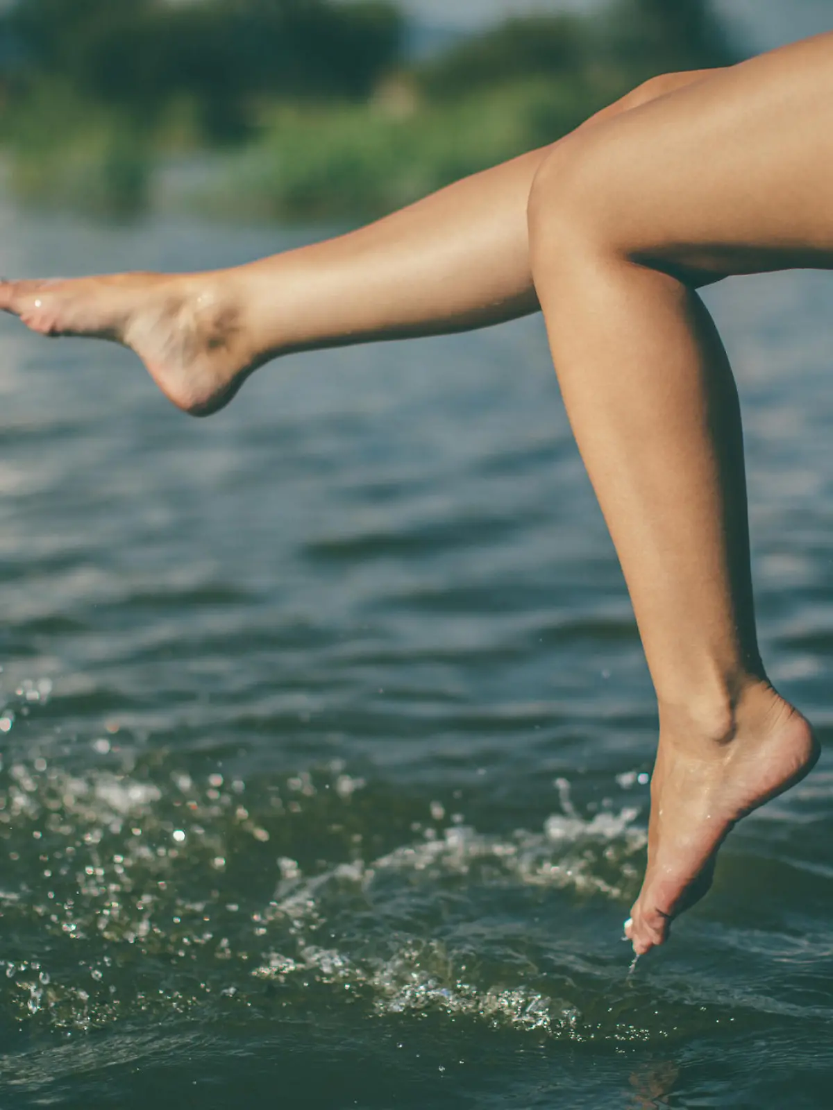 Young woman splashing water with beautiful legs at lake