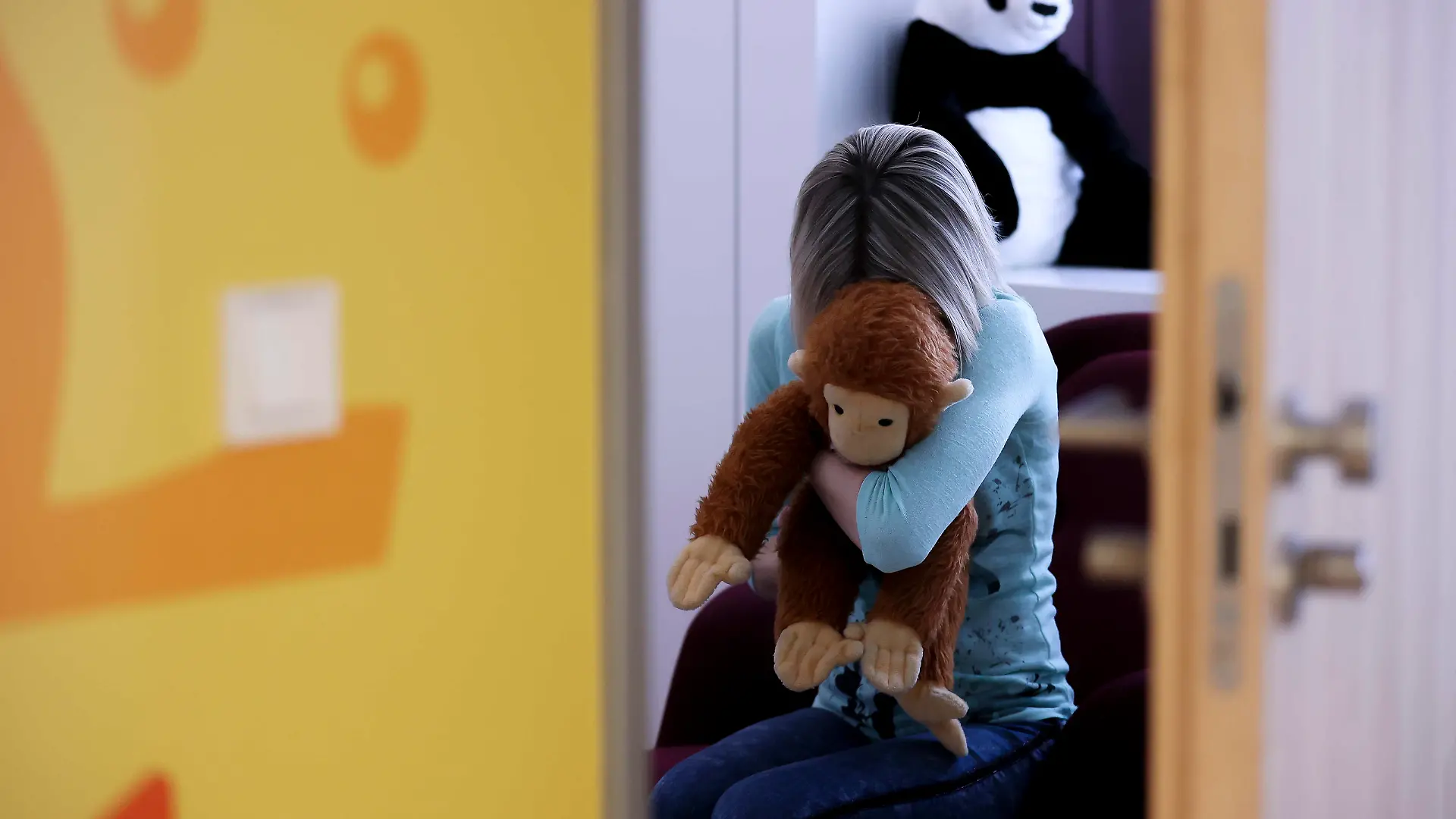 ARCHIV - 14.03.2022, Sachsen, Leipzig: ILLUSTRATION - Eine junge Frau sitzt mit einem Kuscheltier im Arm in einem Raum des Childhood House, in dem Kinder und Jugendliche, die von Missbrauchs betroffen sind, vernommen werden können (gestellte Szene). (zu dpa: «Gesetz zu Umgang mit sexuellem Missbrauch soll im Juni ins Kabinett») Foto: Jan Woitas/dpa +++ dpa-Bildfunk +++