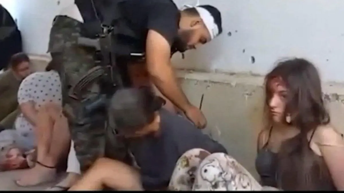 A Gazan militant binds the hands of Daniela Gilboa as other female hostages who are Israeli soldiers, including Karina Ariev, sit on the ground during their capture by Gazan militants at Nahal Oz military base in southern Israel on October 7, 2023, in this screen grab taken from a video released on May 22, 2024. The Hostages Families Forum/Handout via REUTERS THIS IMAGE HAS BEEN SUPPLIED BY A THIRD PARTY. IN-FRAME SUBTITLE FROM SOURCE