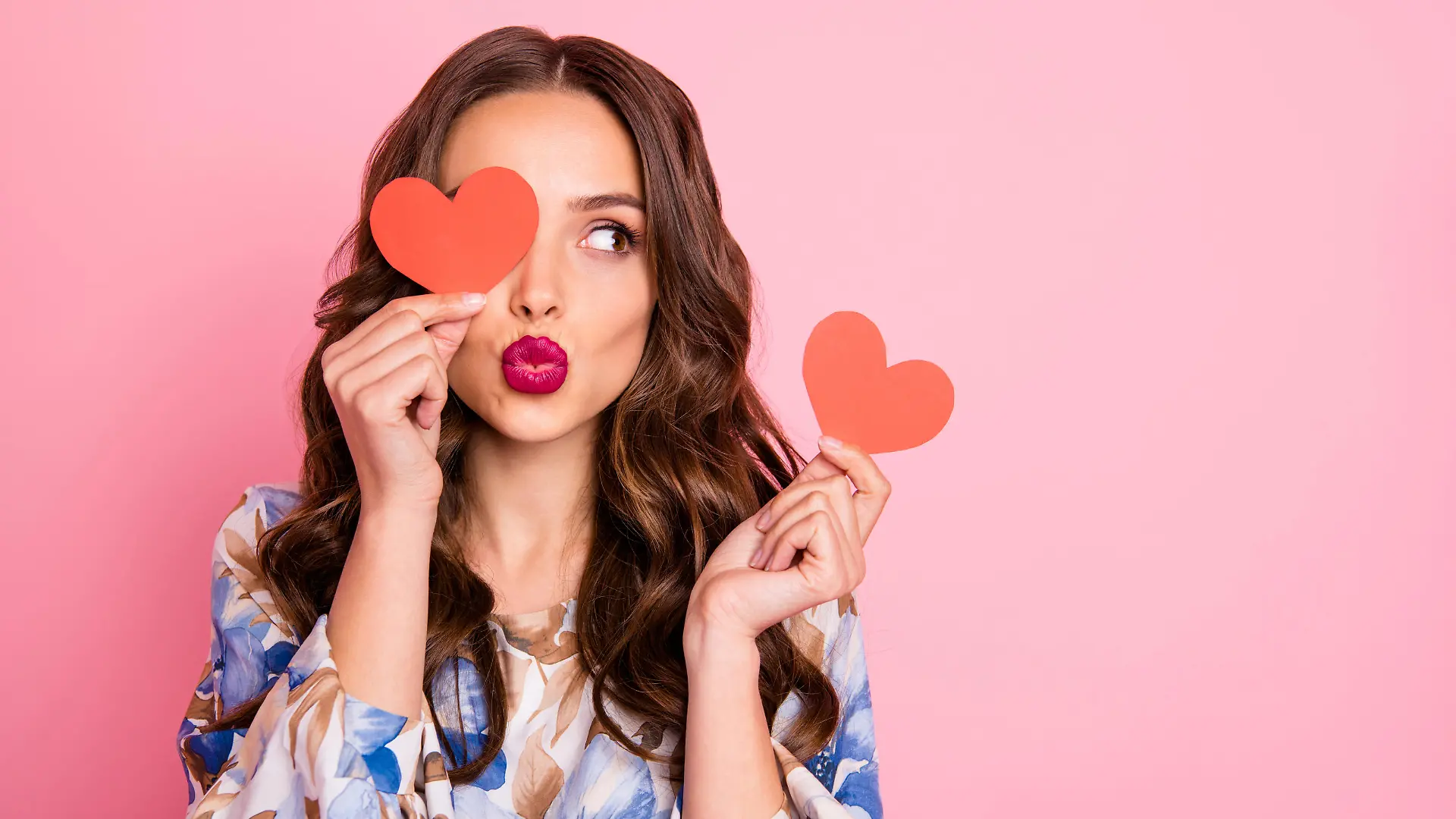 Close-up portrait of her she, nice-looking attractive lovely coquettish cheerful cheery wavy-haired girl holding in hands two small little heart sending you kiss isolated over pink pastel background