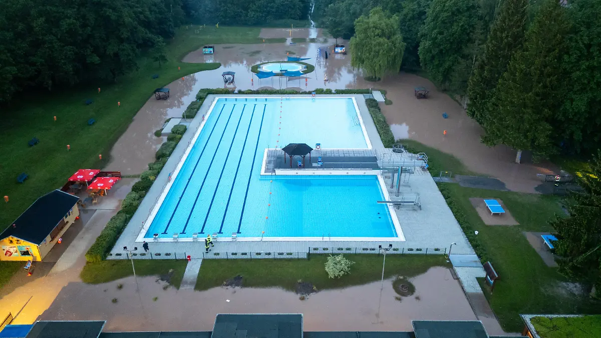 25.05.2024 / Bad Berka / Kurz nach 20 Uhr kam es heute in Bad Berka, Neusaalborn und Blankenhain zu einem Unwetter mit Starkregen. Laut Augenzeugen sind innerhalb kürzester Zeit mehr als 30 Liter Regen gefallen. Das Wasser schoss über die Felder von Blankenhain (nähe Golfresort, wo in den kommenden Tagen die Deutsche Nationalmannschaft trainiert) durch Neusaalborn und Bad Berka. In Bad Berka richtete das Hochwasser starke Schäden am Freibad der Stadt an. Der Klingelbach, welcher neben dem Freibad einen Bachlauf hat, trat innerhalb kürzester Zeit massiv über die Ufer und überflutete das Gelände des Freibads. Das Wasser stand in den Gebäuden des Bads mehr als 30 cm hoch. Glücklicherweise wurde die Pumpenanlage nicht beschädigt.
Die Schäden am Freibad sind dennoch sehr hoch. Die Feuerwehr pumpte am Abend mit einer Saugpumpe Wasser ab. Einsatzkräfte entfernten mit Wasserschiebern Wasser aus dem Gebäude.
In den kommenden Tagen muss das Freibad geschlossen bleiben. Dann wird geprüft, wie hoch die Schäden sind.
Auch im Stadtgebiet von Bad Berka sorgte das Wasser für diverse Schäden. Die Trebestraße wurde komplett überflutet. Hier musste die Feuerwehr die Straße sperren und aufwendig beräumen.
Ob es Schäden rund um das Golfresort bei Blankenhain gibt, lässt sich zum Stand heute Abend nicht sagen. Augenzeugen berichteten hier, dass das Wasser sich auch hier seinen Weg suchte.
/ Foto: Johannes Krey | JKFTV.de