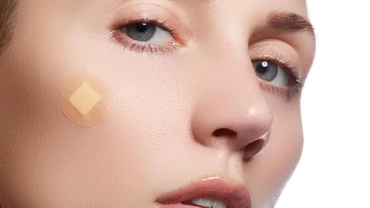 Close-up portrait of beautiful woman's purity face with natural make-up. Cute model with clean shiny skin. Beautiful young woman with clear-up patches or plaster on her skin. Skin care concept