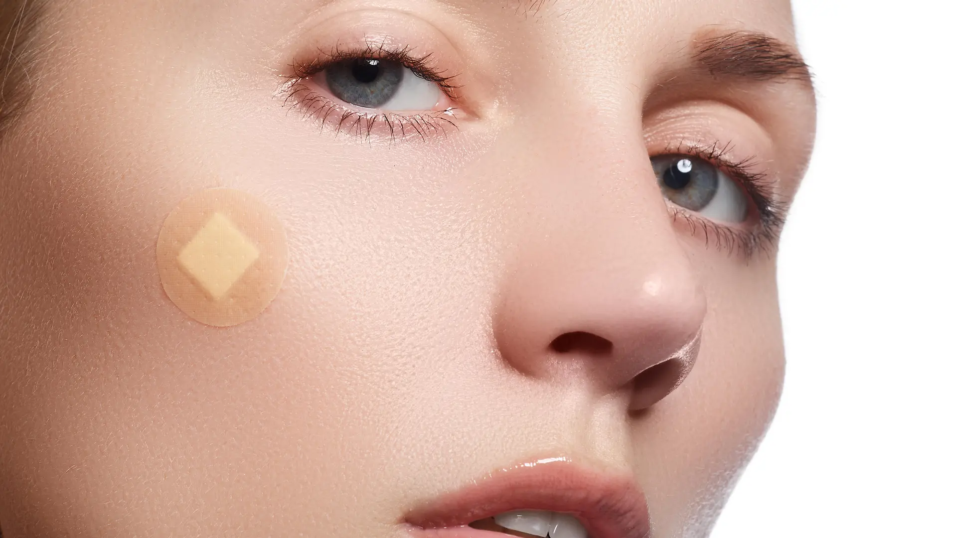 Close-up portrait of beautiful woman's purity face with natural make-up. Cute model with clean shiny skin. Beautiful young woman with clear-up patches or plaster on her skin. Skin care concept