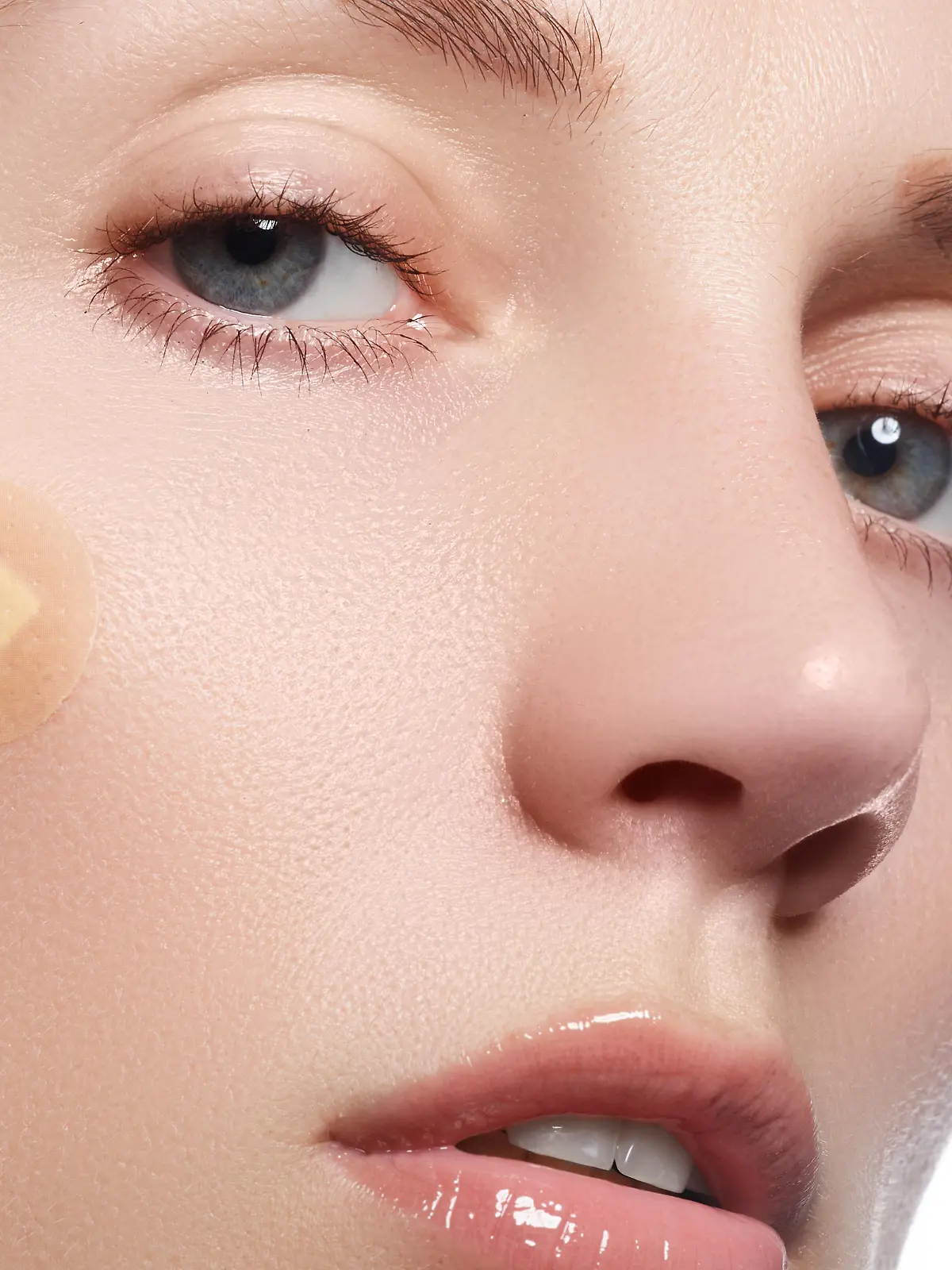 Close-up portrait of beautiful woman's purity face with natural make-up. Cute model with clean shiny skin. Beautiful young woman with clear-up patches or plaster on her skin. Skin care concept