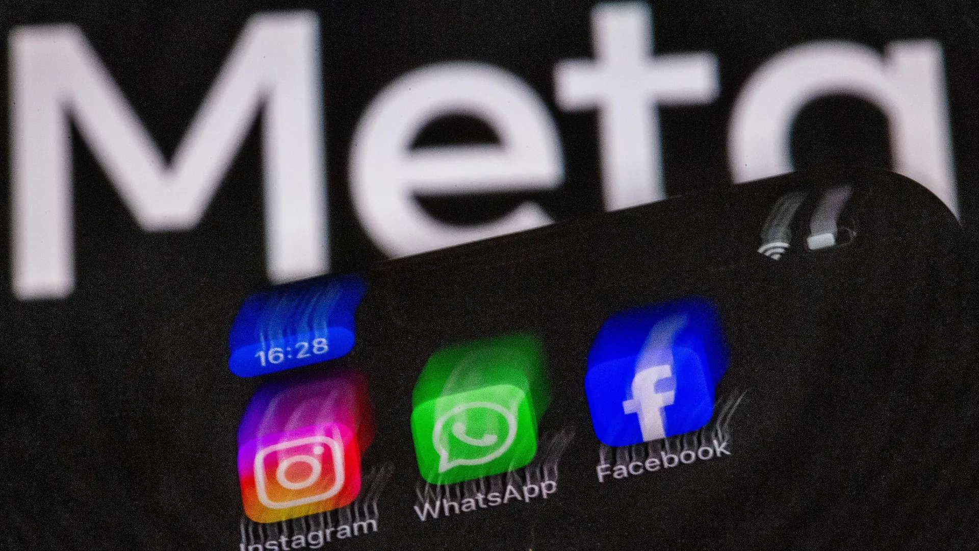 ILLUSTRATION - 16.05.2024, Mecklenburg-Vorpommern, Schwerin: ILLUSTRATION - Die Apps Instagram, Facebook und WhatsApp sind auf dem Display eines Smartphones vor dem Logo des Internetkonzerns Meta zu sehen. Die Internetprogramme gehören zum Unternehmen Meta, der Dachmarke des Facebook-Konzerns. Die Europäische Kommission eröffnet wegen des Verdachts auf Verstöße gegen den Jugendschutz ein Verfahren gegen den Facebook- und Instagram-Mutterkonzern Meta. Foto: Jens Büttner/dpa +++ dpa-Bildfunk +++