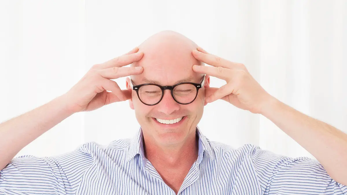 portrait of a bald-headed man with his eyes closed and smiling