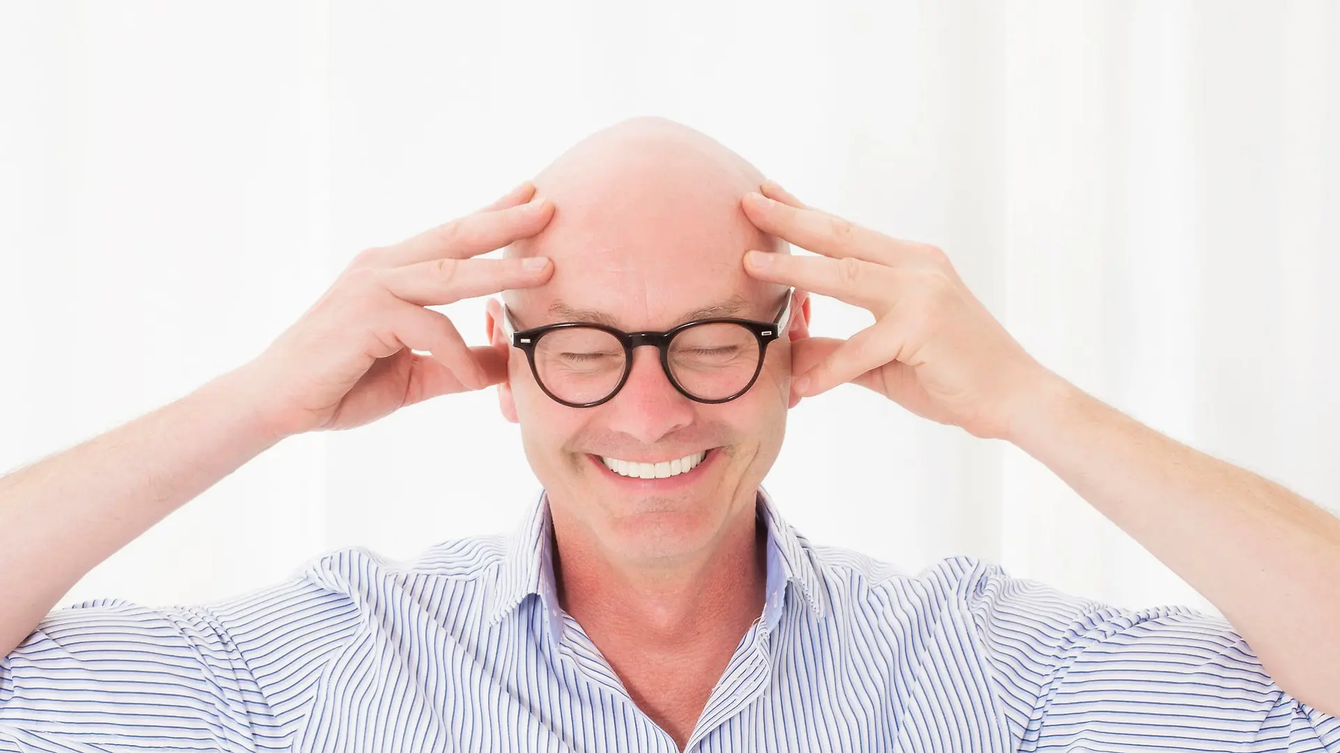 portrait of a bald-headed man with his eyes closed and smiling