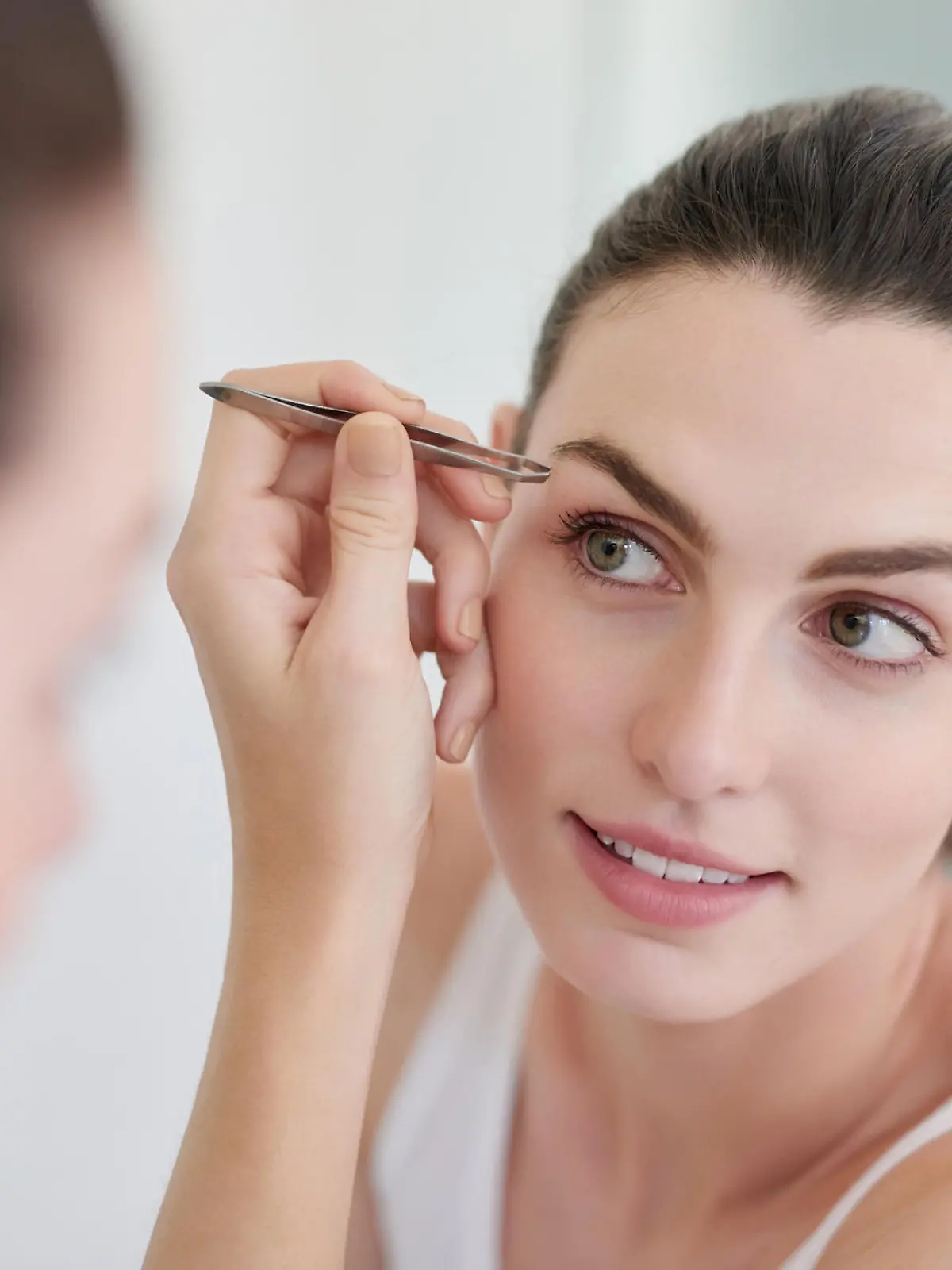 Shot of a beautiful young woman plucking her eyebrows with a pair of tweezers