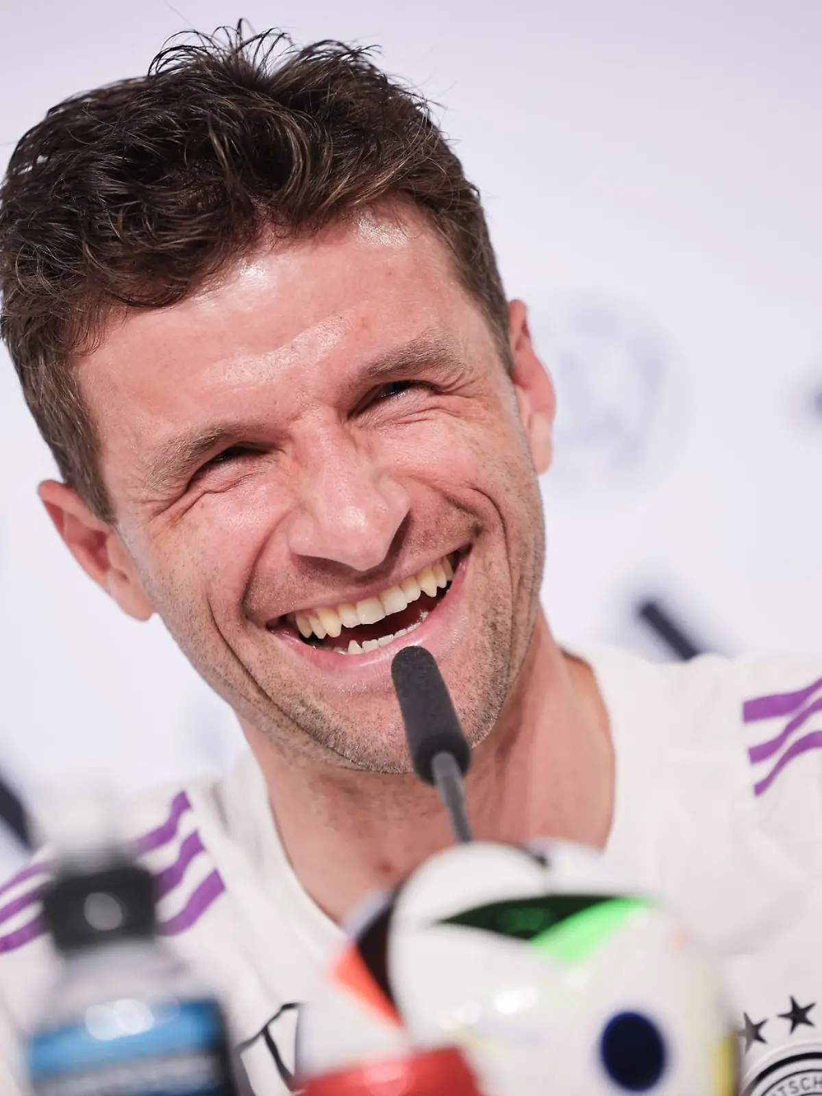 Thomas Müller lacht auf der Pressekonferenz.