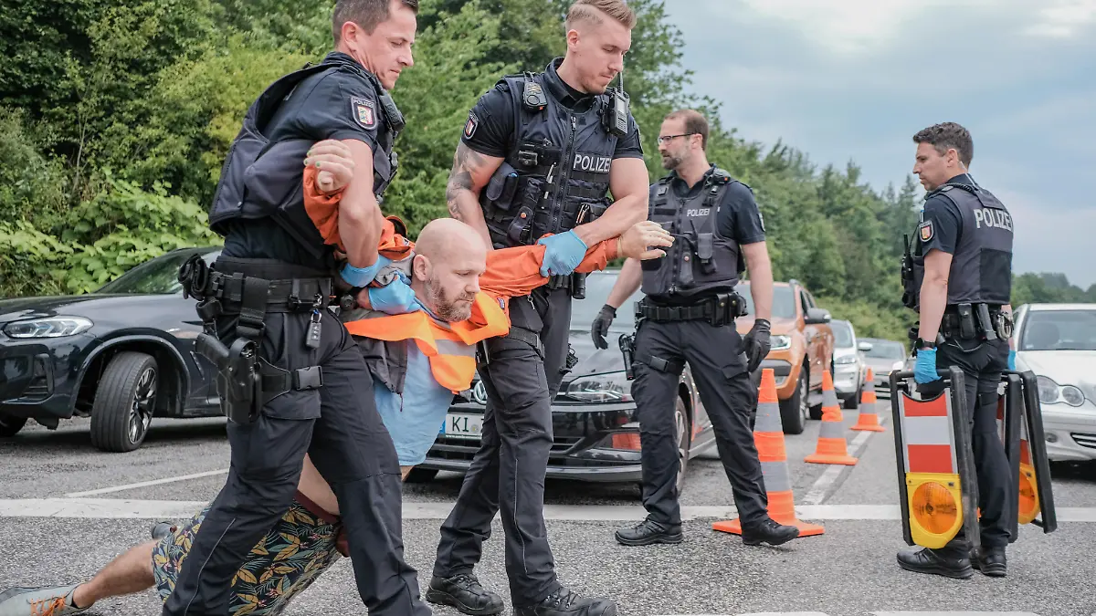 Sechs Aktivist*innen der Letzten Generation blockierten am 10.7.2023 die Ausfahrt der Bundesstrasse 76 in Kiel. Die Letzte Generation fordert ein Tempolimit von 100 km/h auf Autobahnen, die Einfuehrung eines Neun-Euro-Tickets und einen Gesellschaftsrat Klima. -- 6 activists of the Last Generation blocked the exit ramp of the B76 in Kiel, Germany. The Last Generation demands a speed limit of 100 km/h on highways, the introduction of a nine-euro ticket and a Climate Society Council.