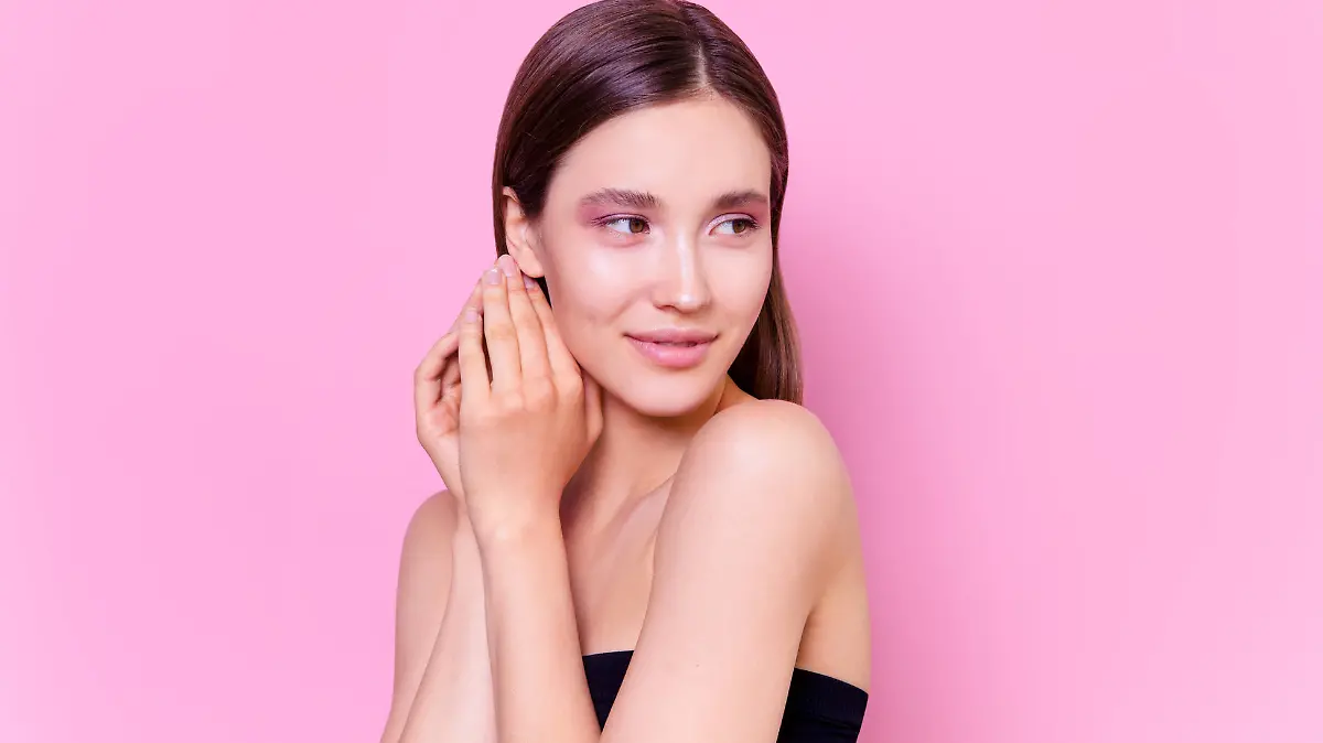 Beautiful brunette young woman on pink background Fashion model close-up beauty shot Flawless skin perfect nude colored glowing make up
