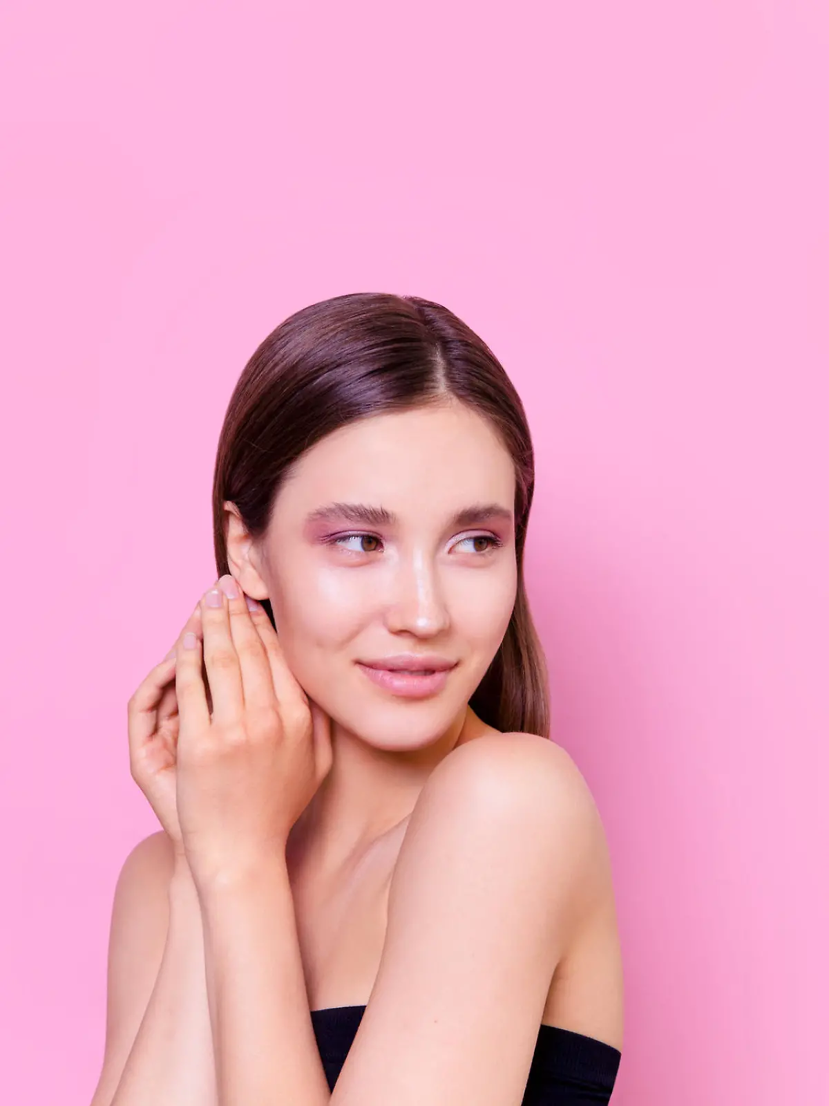 Beautiful brunette young woman on pink background Fashion model close-up beauty shot Flawless skin perfect nude colored glowing make up