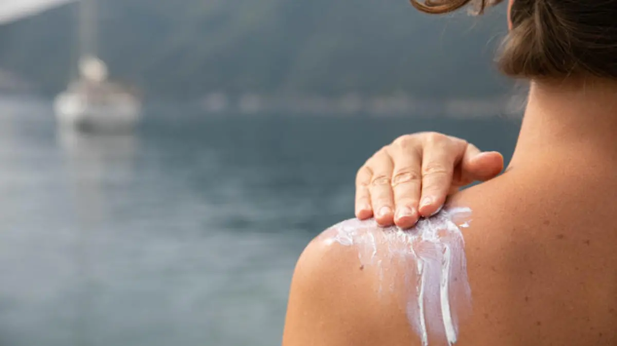 Hand of a woman applying sun cream with her back turned