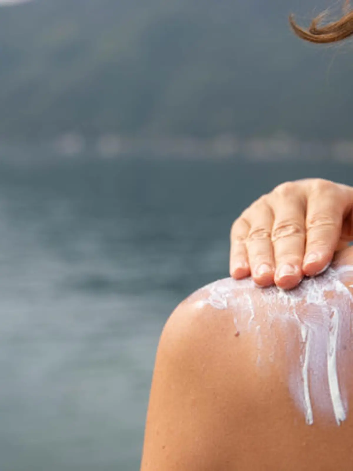 Hand of a woman applying sun cream with her back turned