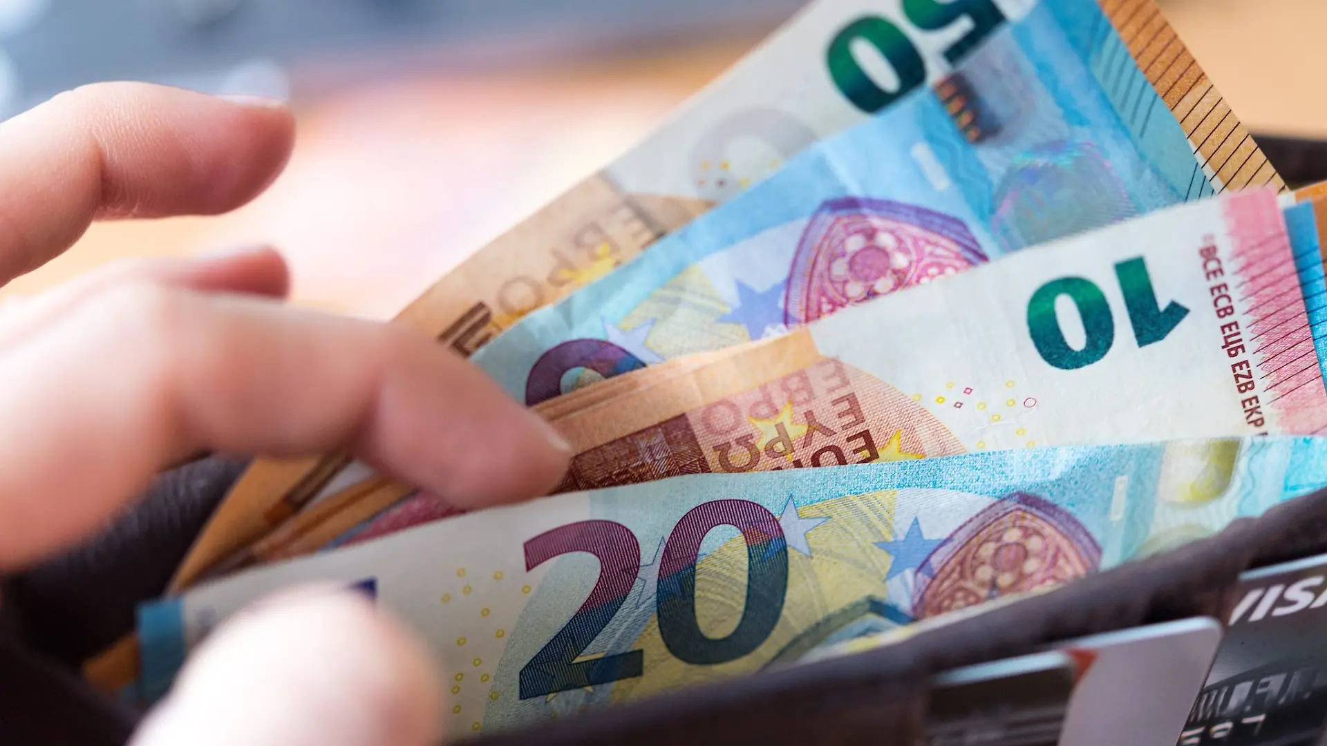 Eine Frau hält eine Geldbörse mit Banknoten in der Hand.