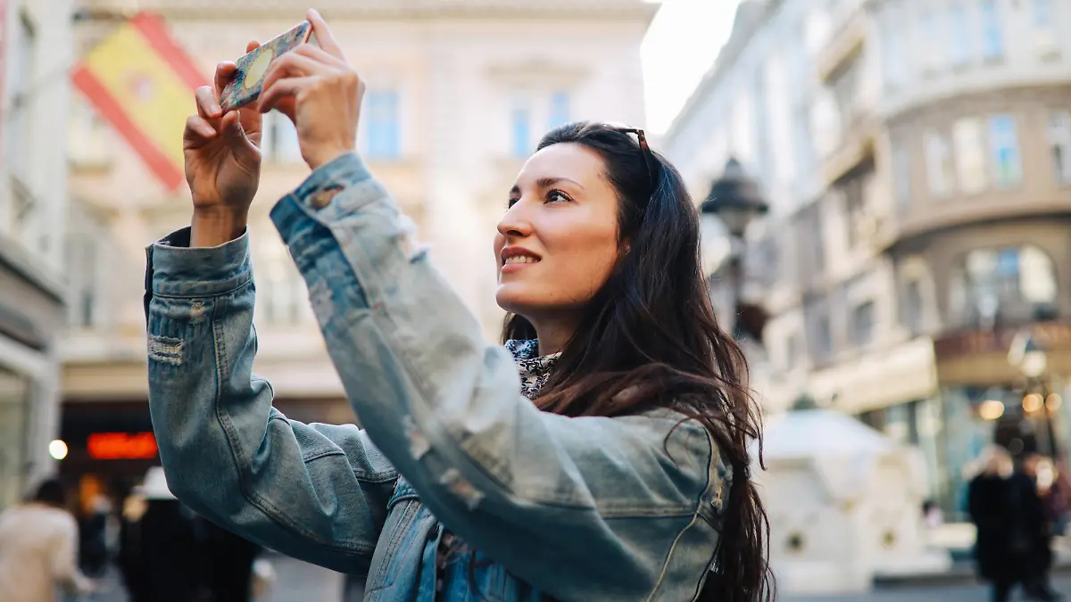 Young tourist woman on a city break, using her smartphone to snap some photographs.