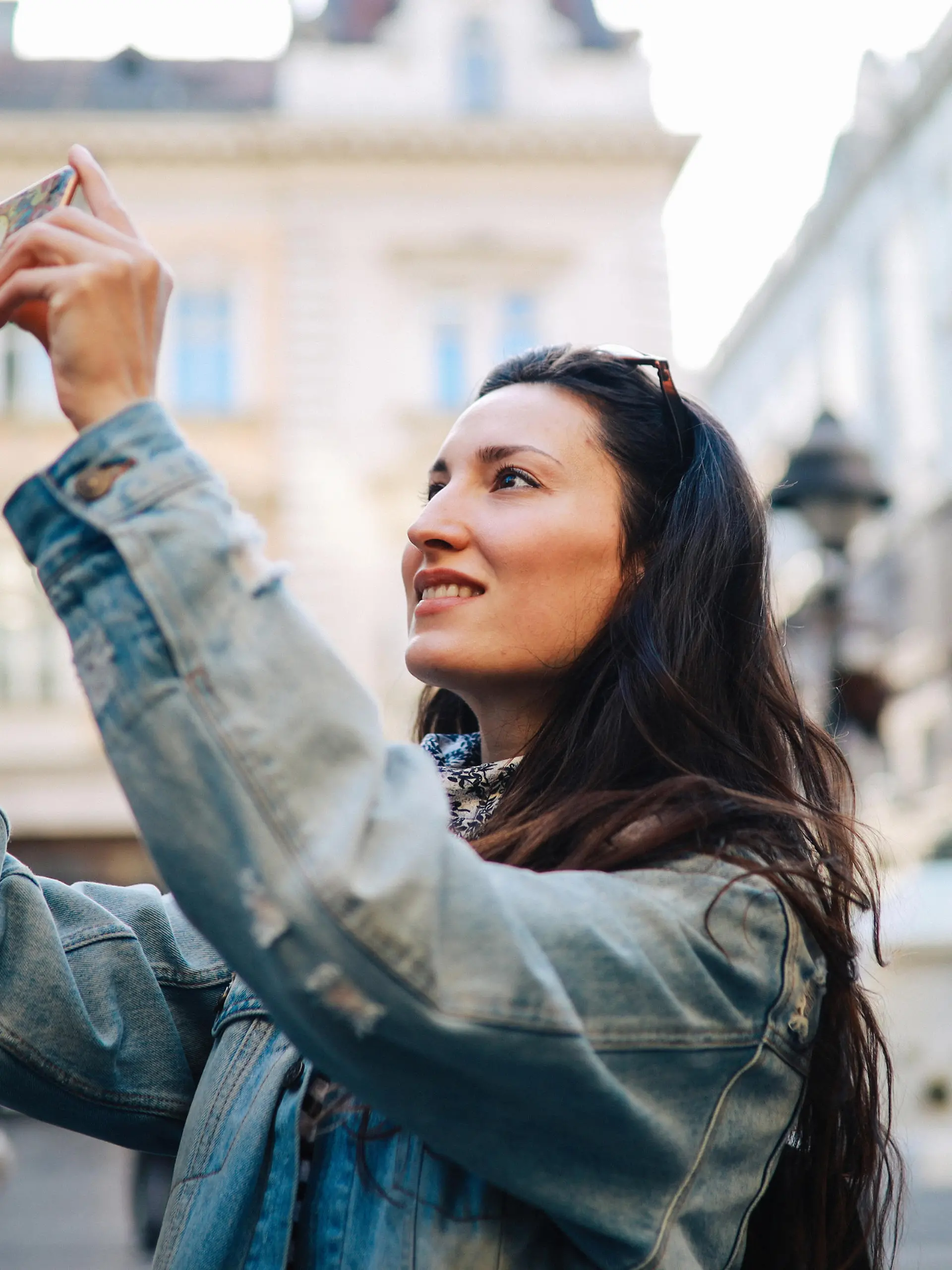 Young tourist woman on a city break, using her smartphone to snap some photographs.
