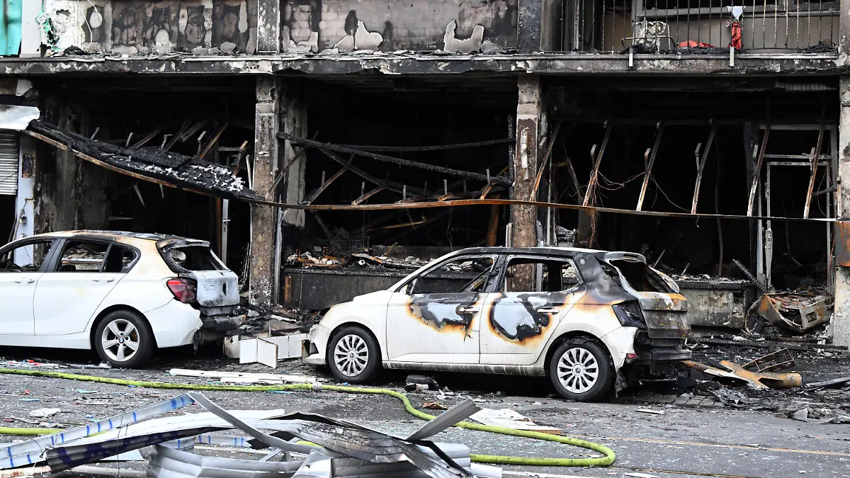 ARCHIV - 16.05.2024, Nordrhein-Westfalen, Düsseldorf: Ausgebrannte Autos stehen vor einem Wohnhaus, in dem ein Brand wütete. Bei dem Brand in Düsseldorf sind mehrere Menschen ums Leben gekommen und weitere verletzt worden. Wie die Feuerwehr mitteilte, war in der Nacht zum Donnerstag aus bislang ungeklärter Ursache ein in einem Wohnhaus integrierter Kiosk in Brand geraten. (zu dpa: «Ermittler sehen Kioskbetreiber als Verursacher der tödlichen Explosion») Foto: Federico Gambarini/dpa +++ dpa-Bildfunk +++