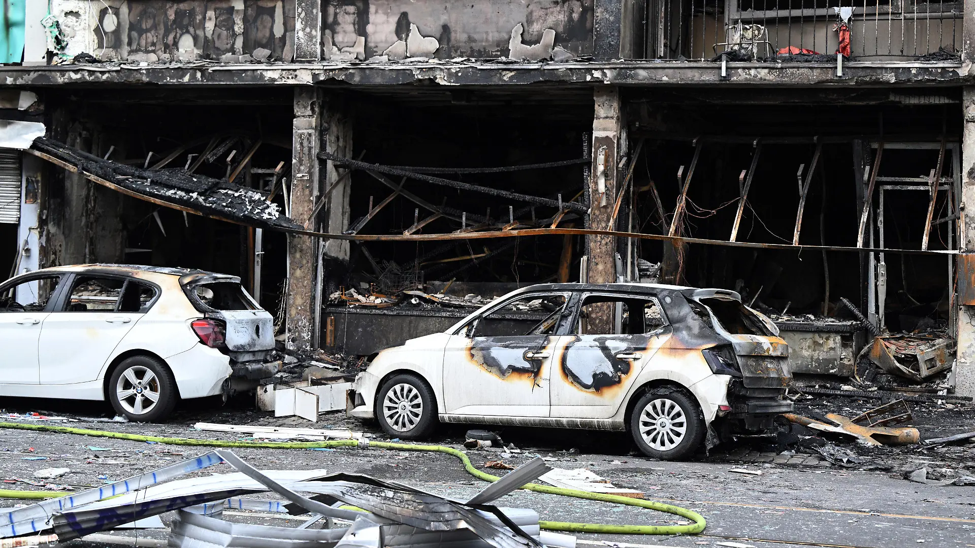 ARCHIV - 16.05.2024, Nordrhein-Westfalen, Düsseldorf: Ausgebrannte Autos stehen vor einem Wohnhaus, in dem ein Brand wütete. Bei dem Brand in Düsseldorf sind mehrere Menschen ums Leben gekommen und weitere verletzt worden. Wie die Feuerwehr mitteilte, war in der Nacht zum Donnerstag aus bislang ungeklärter Ursache ein in einem Wohnhaus integrierter Kiosk in Brand geraten. (zu dpa: «Ermittler sehen Kioskbetreiber als Verursacher der tödlichen Explosion») Foto: Federico Gambarini/dpa +++ dpa-Bildfunk +++