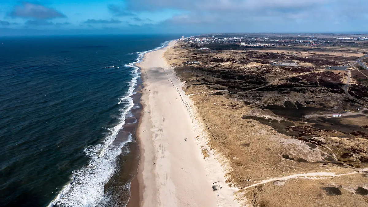 03.04.2021, Schleswig-Holstein, Westerland/Sylt: Einige Menschen laufen bei strahlendem Sonnenschein über den Sandstrand der Ostseite der Insel Sylt (im Hintergrund ist die Stadt Westerland zu sehen). (Luftbild mit Drohne) Foto: Axel Heimken/dpa +++ dpa-Bildfunk +++
