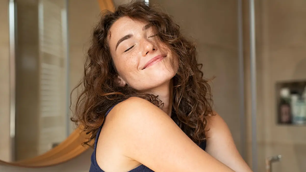 Happy young woman feeling relaxed with eyes closed. Smiling woman stretching with hands forward feeling fresh on a bright morning. Beautiful girl stretch herself in the morning..