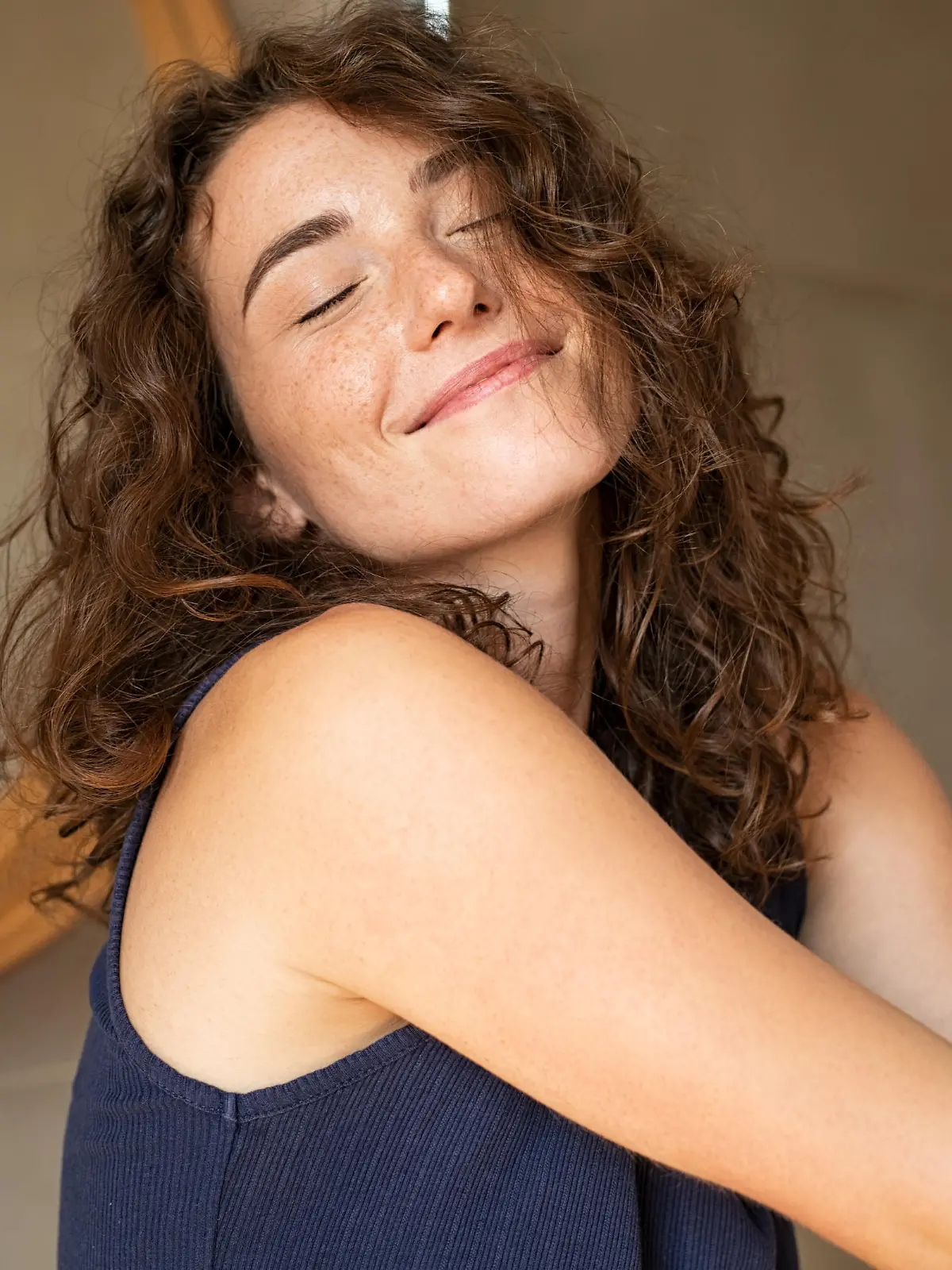 Happy young woman feeling relaxed with eyes closed. Smiling woman stretching with hands forward feeling fresh on a bright morning. Beautiful girl stretch herself in the morning..