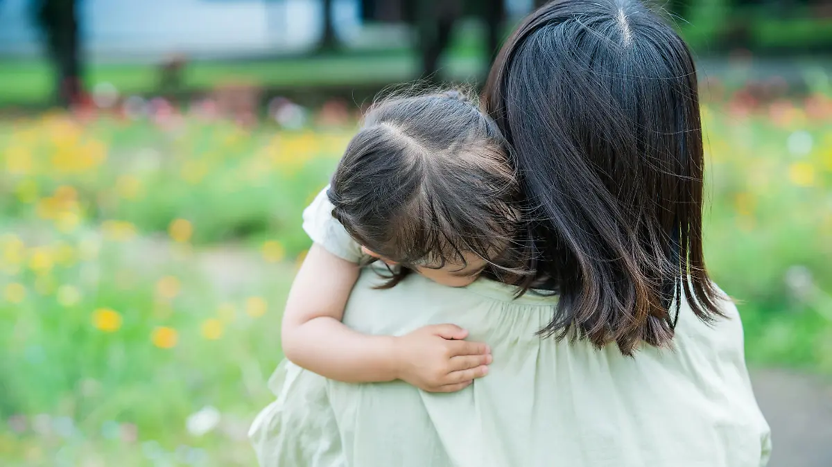 A girl who is tired of playing and is hugged by her mother