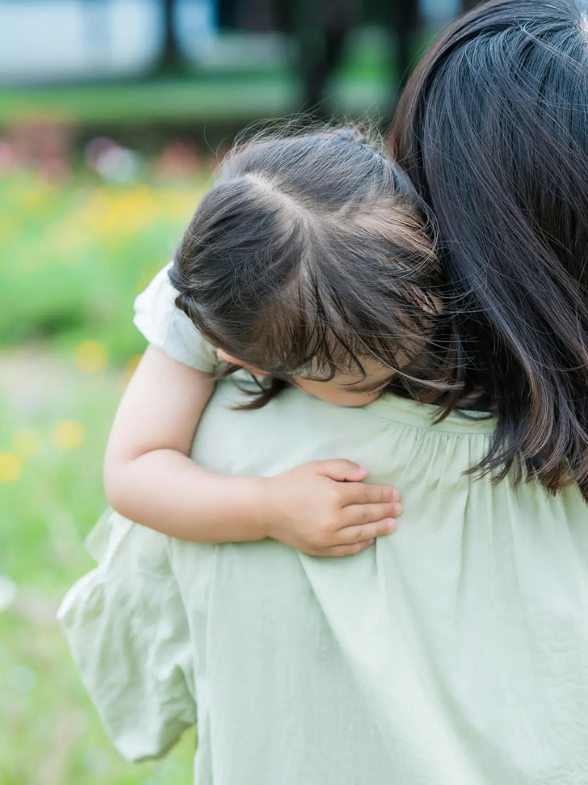 A girl who is tired of playing and is hugged by her mother