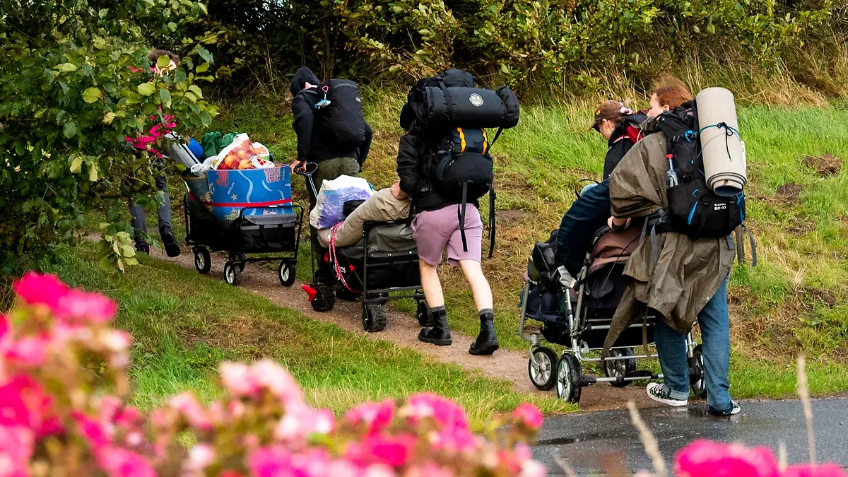 Punks der Gruppe «Aktion Sylt» gehen im Sommer 2023 am Abend im Ort Tinnum zu der Wiese, auf der ein Protestcamp stattfinden soll.