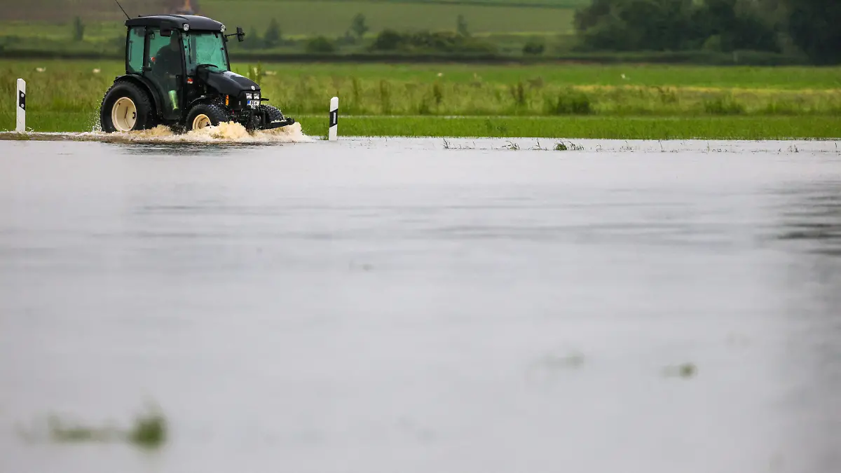 01.06.2024, Baden-Württemberg, Riedlingen: Ein Traktor fährt auf der überfluteten Kreisstraße zwischen Unlingen und Daugendorf. Foto: Thomas Warnack/dpa +++ dpa-Bildfunk +++