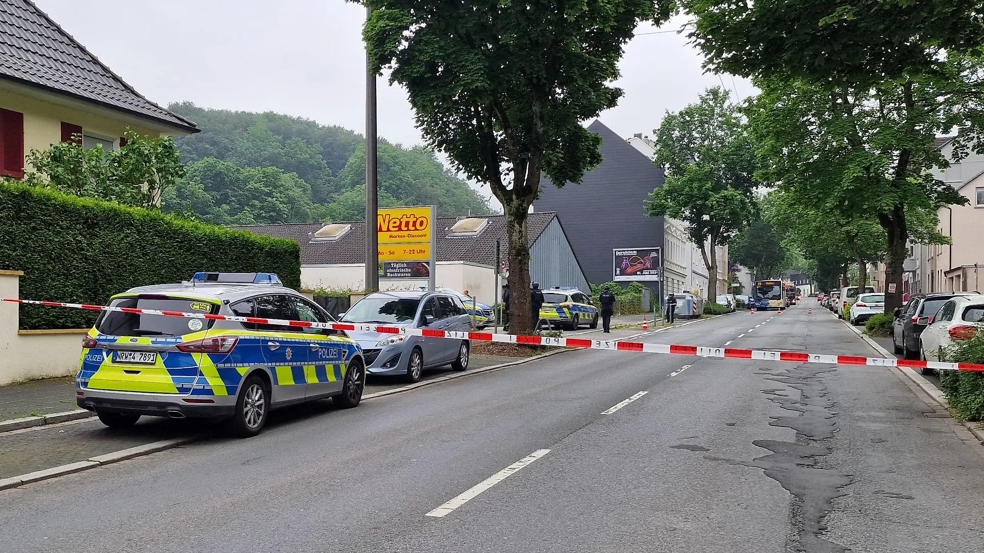 01.06.2024, Nordrhein-Westfalen, Hagen: Einsatzfahrzeuge der Polizei stehen in einer abgesperten Straße.Durch Schüsse an zwei Orten sind am Samstag in Hagen insgesamt vier Menschen verletzt worden. Eine Person habe lebensgefährliche Verletzungen erlitten, sagte ein Sprecher der federführenden Polizei Dortmund. Nähere Angaben machte die Polizei zunächst nicht. Ein Täter befand sich am frühen Samstagnachmittag laut Polizei auf der Flucht. Nach ihm werde mit Hochdruck gefahndet. Die Polizei Dortmund schloss aber auch nicht aus, dass es mehrere Täter geben könne. Foto: Justin Brosch/dpa +++ dpa-Bildfunk +++
