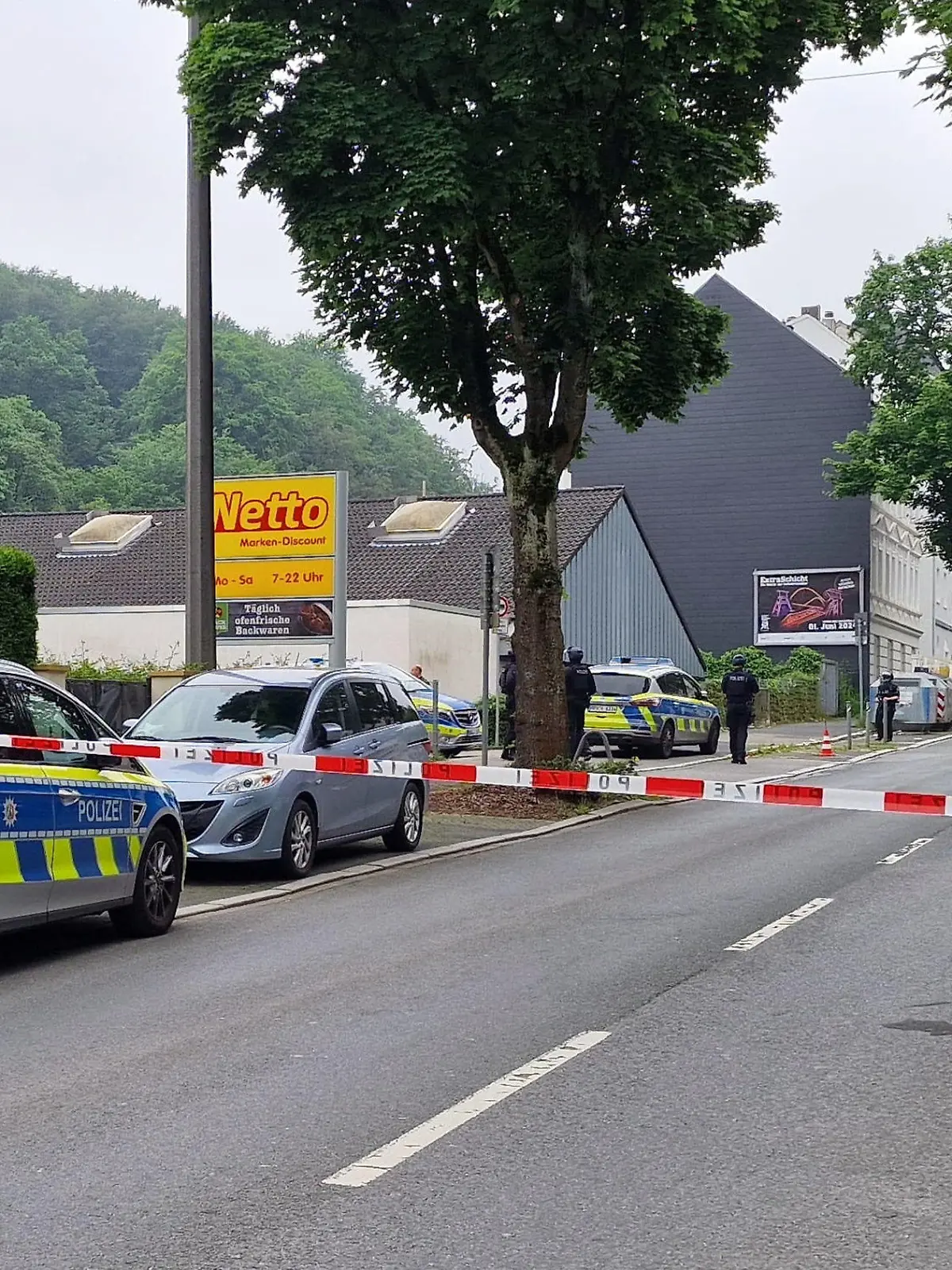 01.06.2024, Nordrhein-Westfalen, Hagen: Einsatzfahrzeuge der Polizei stehen in einer abgesperten Straße.Durch Schüsse an zwei Orten sind am Samstag in Hagen insgesamt vier Menschen verletzt worden. Eine Person habe lebensgefährliche Verletzungen erlitten, sagte ein Sprecher der federführenden Polizei Dortmund. Nähere Angaben machte die Polizei zunächst nicht. Ein Täter befand sich am frühen Samstagnachmittag laut Polizei auf der Flucht. Nach ihm werde mit Hochdruck gefahndet. Die Polizei Dortmund schloss aber auch nicht aus, dass es mehrere Täter geben könne. Foto: Justin Brosch/dpa +++ dpa-Bildfunk +++