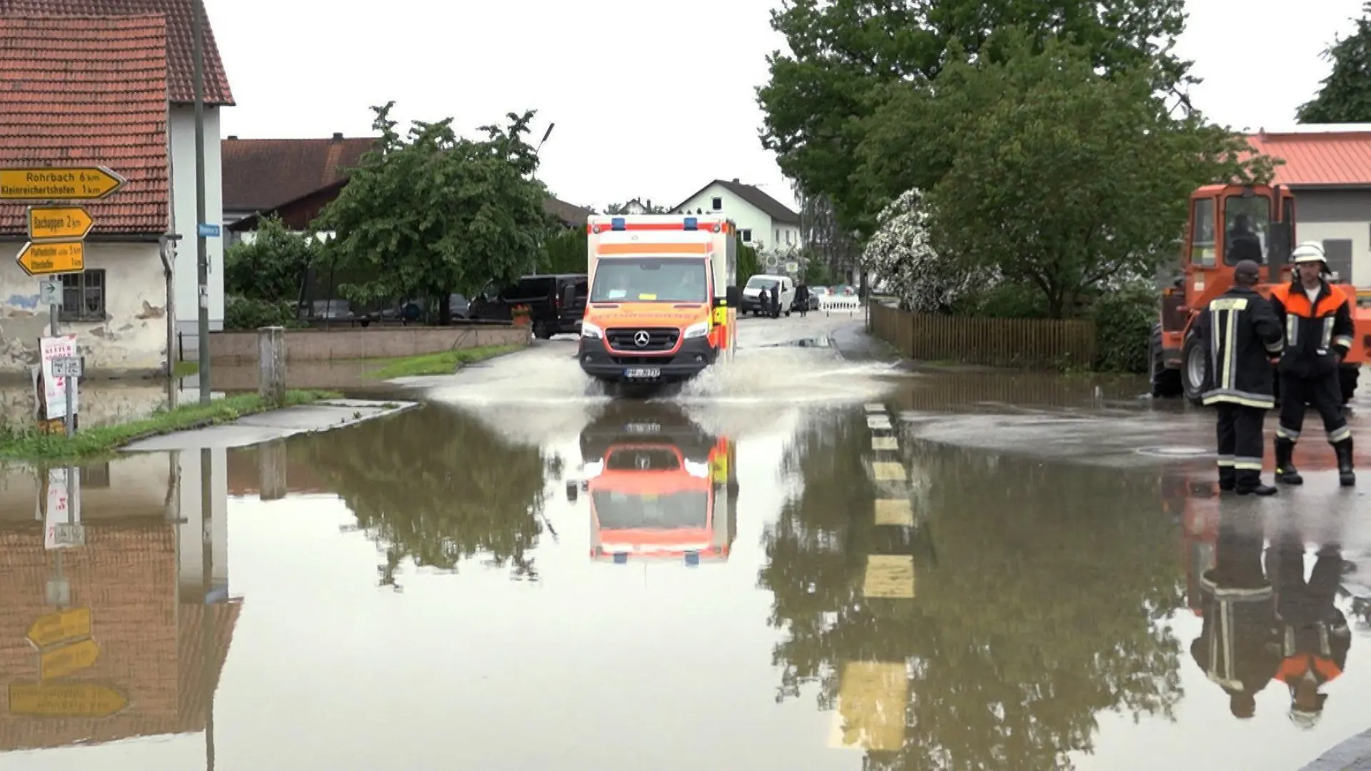 02.06.2024, Bayern, Pfaffenhofen an der Ilm: Ein Krankenwagen fährt über eine überschwemmte Straße in Pfaffenhofen an der Ilm. Ein Feuerwehrmann ist in Pfaffenhofen an der Ilm in Oberbayern ums Leben gekommen. Er sei bei einem Einsatz mit drei Kollegen mit dem Schlauchboot gekentert und am Morgen tot geborgen worden, teilte ein Sprecher des Landratsamts am Sonntagmorgen mit. Foto: -/tv7news/dpa +++ dpa-Bildfunk +++