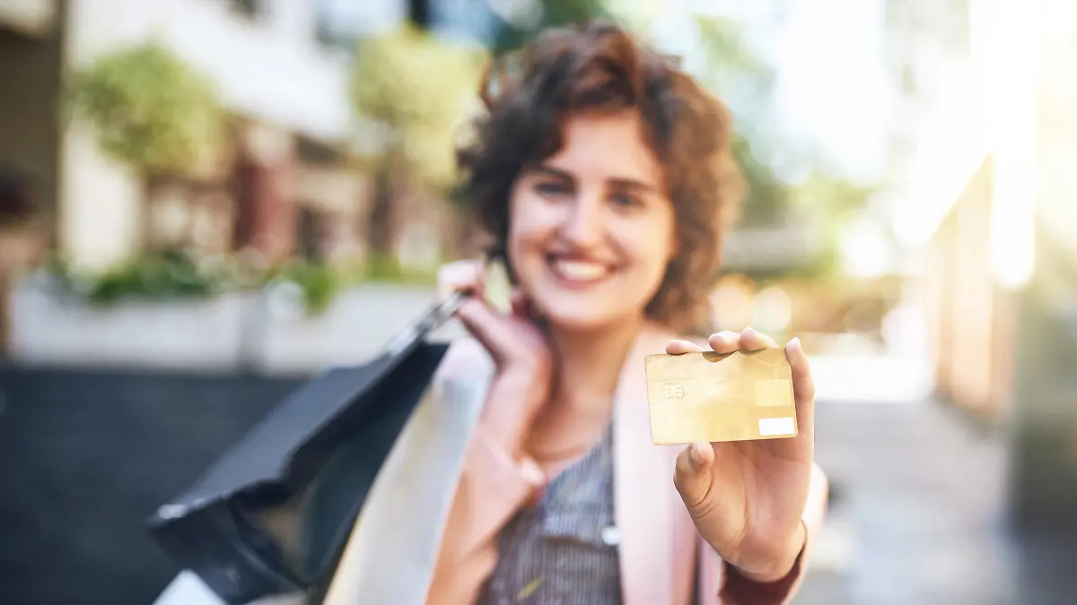 Shot of a woman holding up her credit card while out shopping