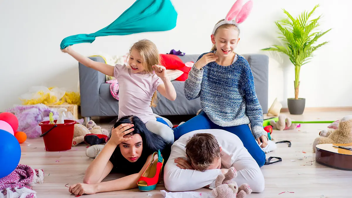Tired parents lying on floor and their romping kids