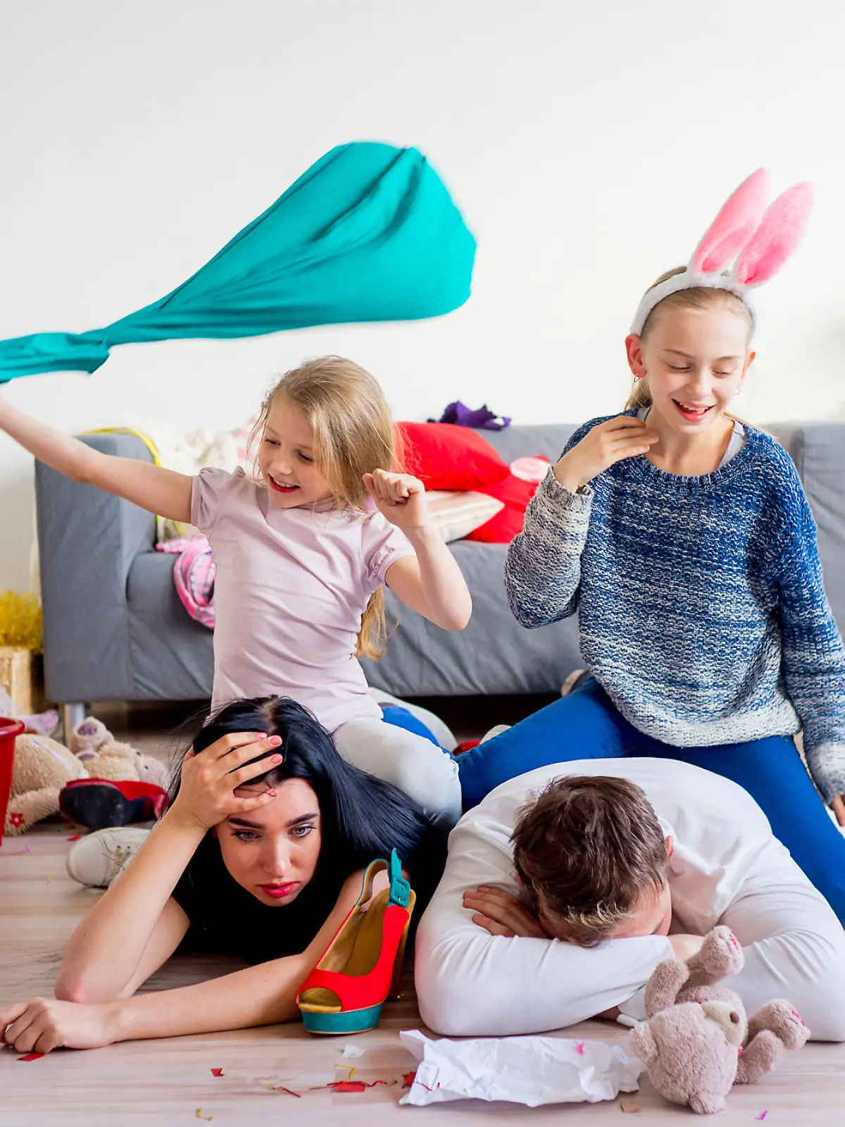 Tired parents lying on floor and their romping kids