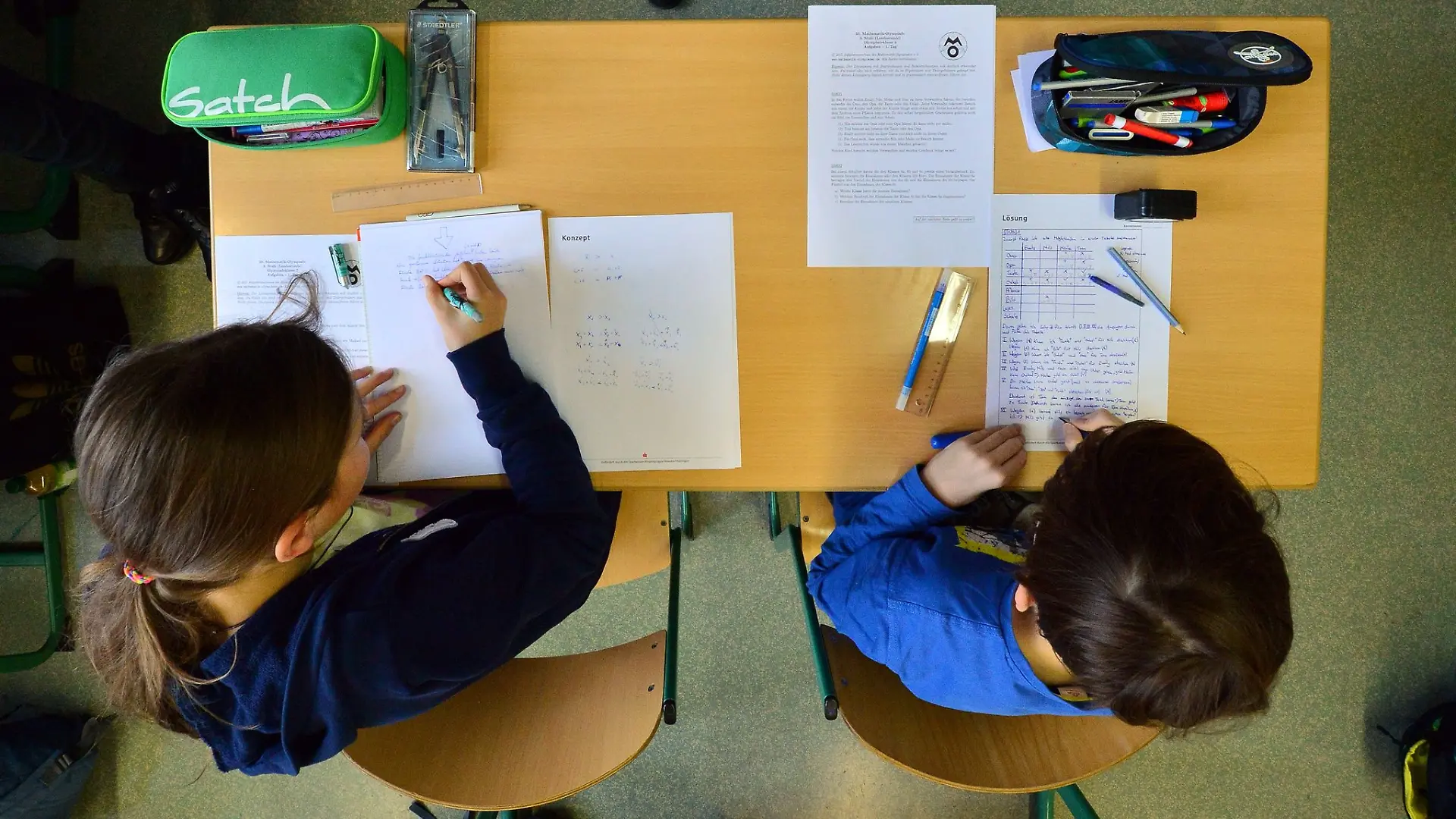 Zwei Schüler sitzen bei einer Mathematik-Olympiade in einem Klassenzimmer.
