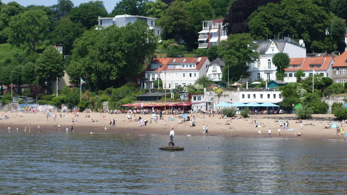 18.06.2023, Hamburg: Menschen entspannen sich bei schönstem Sommerwetter am Elbstrand. Im Vordergrund eine Skulptur in der Elbe, der sogenannte Bojenmann. Foto: Thomas Müller/dpa +++ dpa-Bildfunk +++