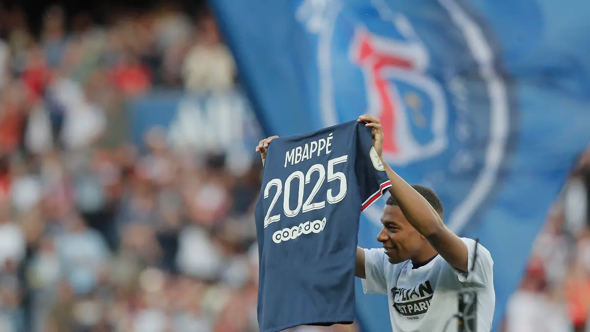 PSG's Kylian Mbappe waves a shirt to the crowd after it is announced that he has signed a three year extension to his deal to stay at the club ahead of the French League One soccer match between Paris Saint Germain and Metz at the Parc des Princes stadium in Paris, France, Saturday, May 21, 2022. (AP Photo/Michel Spingler)