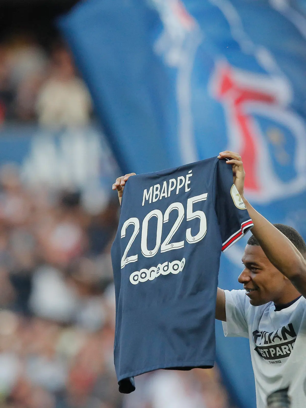 PSG's Kylian Mbappe waves a shirt to the crowd after it is announced that he has signed a three year extension to his deal to stay at the club ahead of the French League One soccer match between Paris Saint Germain and Metz at the Parc des Princes stadium in Paris, France, Saturday, May 21, 2022. (AP Photo/Michel Spingler)