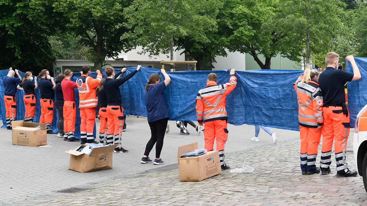 Emergency medical workers cover pupils leaving from a school where shots were fired, in the northern city of Bremerhaven, Germany, May 19, 2022. REUTERS/Fabian Bimmer