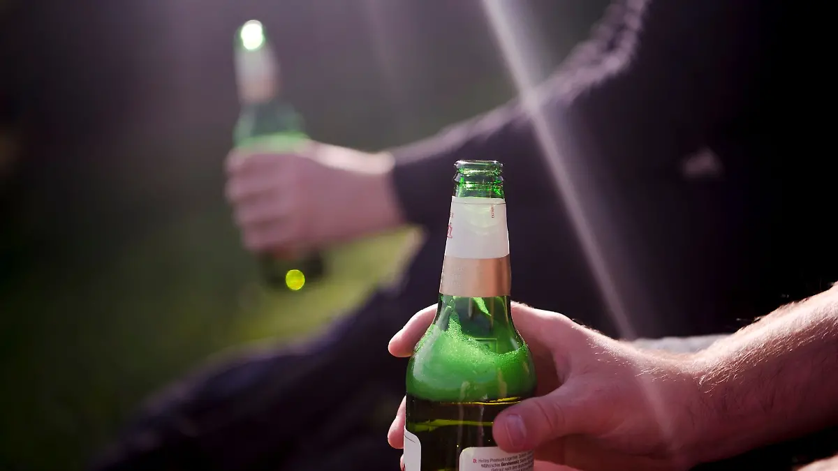 Zwei Männer sitzen im Olympia-Park und trinken Bier.