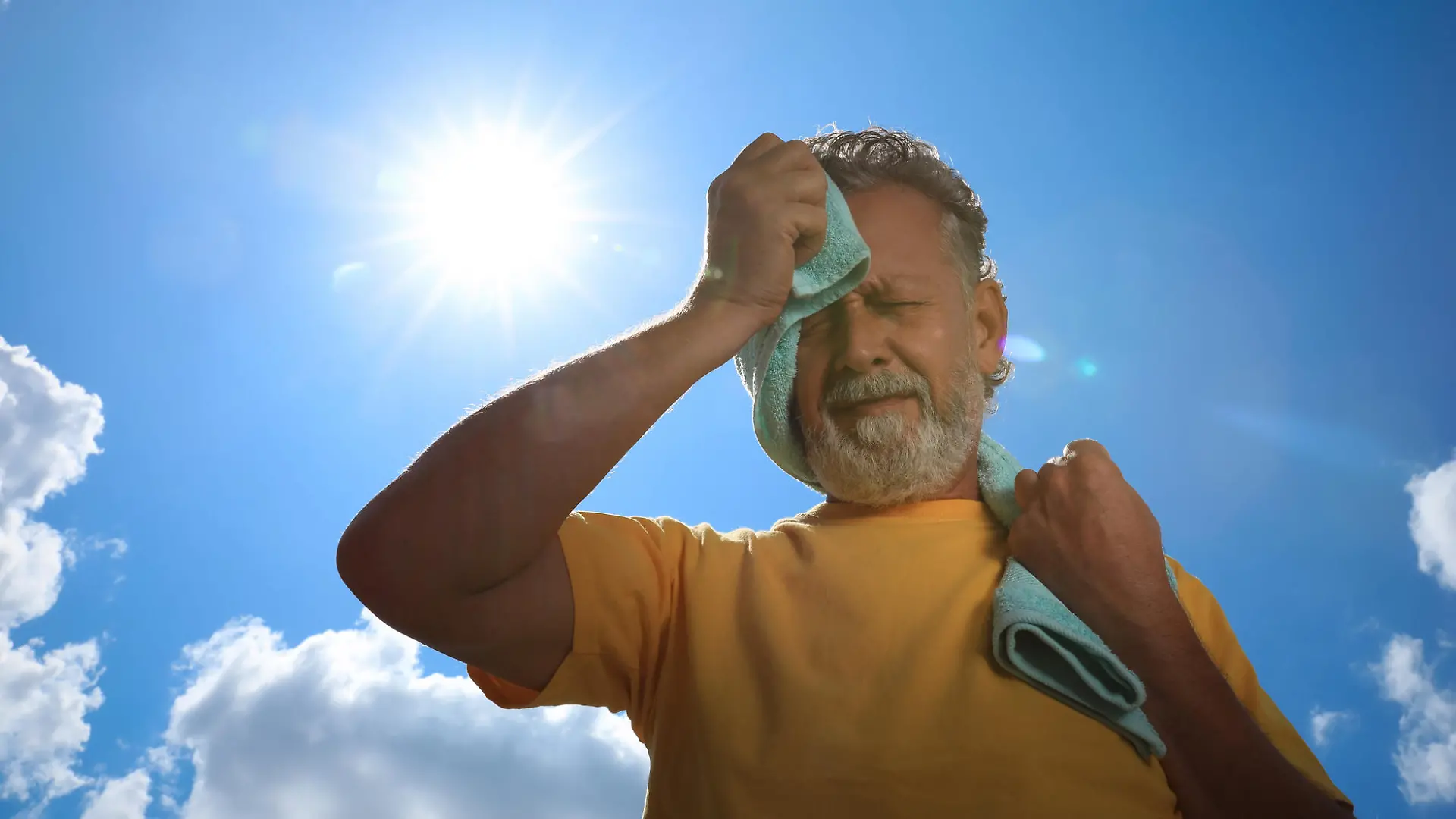 Senior man with towel suffering from heat stroke outdoors, low angle view