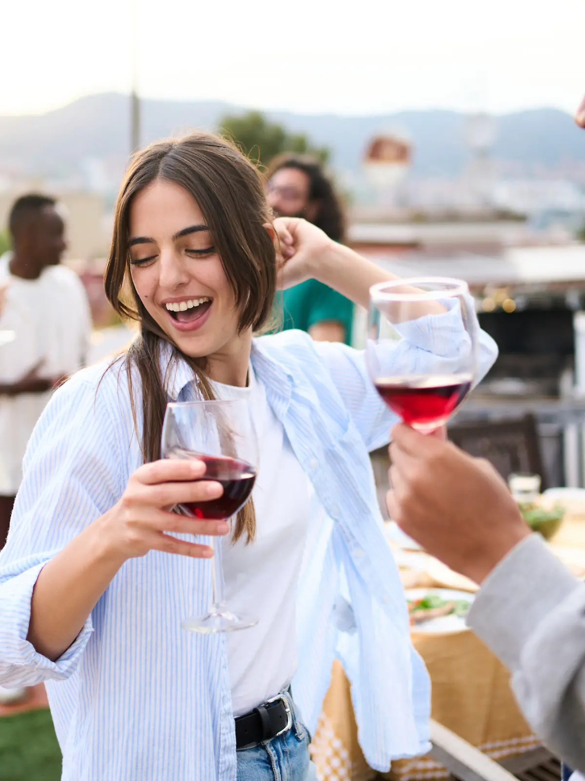 Eine junge Frau tanzt ausgelassen mit einem Glas Wein in der Hand auf einer Party.