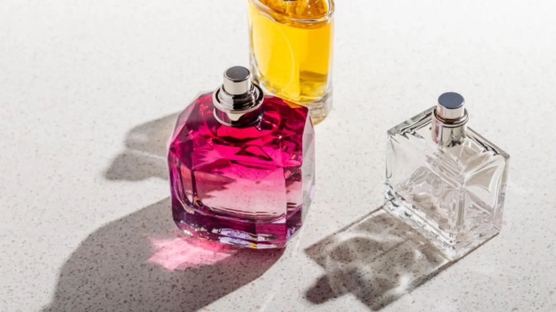 A group of perfume bottles on a white stone background on a sunny day