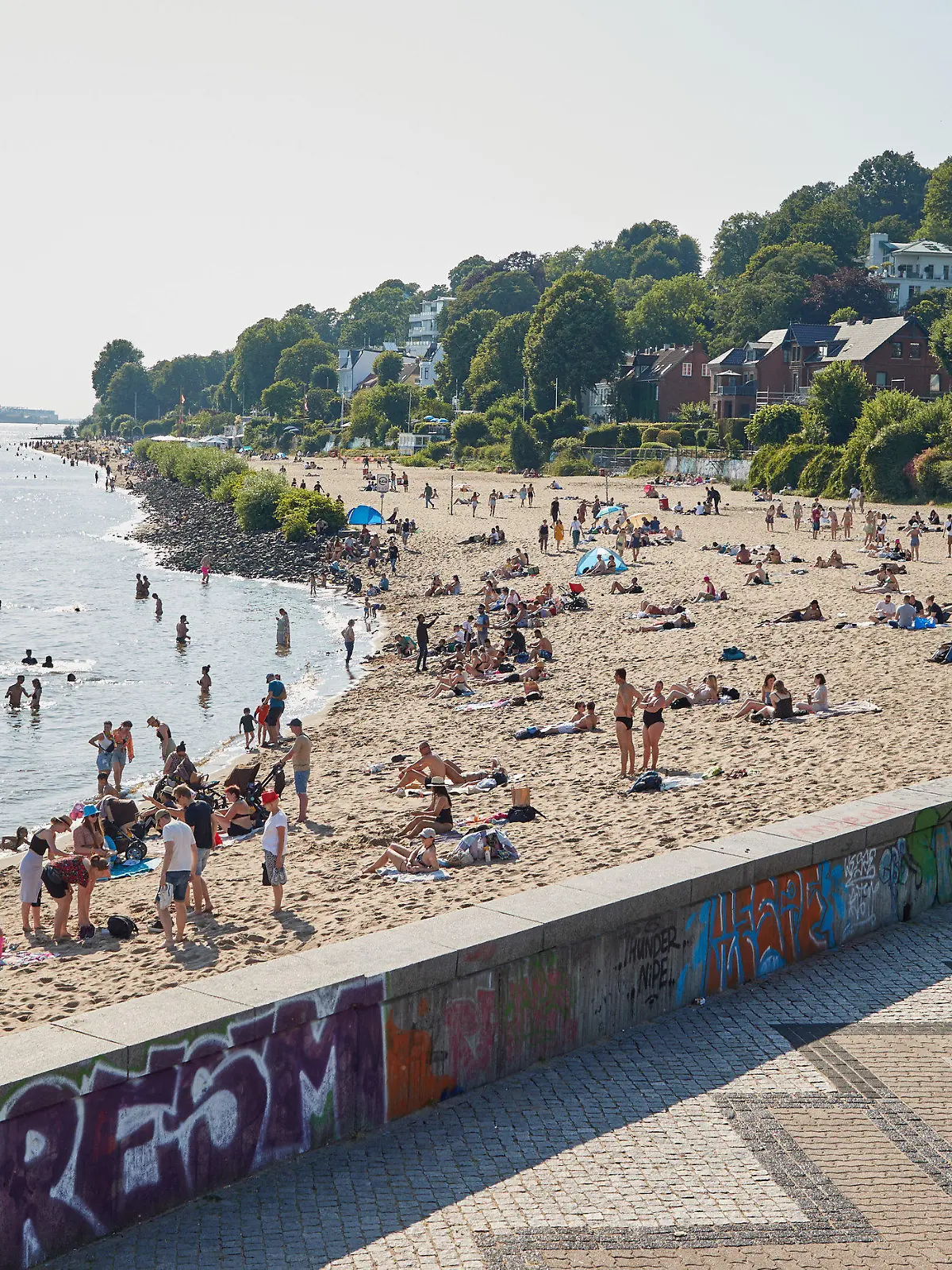 08.07.2023, Hamburg: Menschen genießen die Sonne und das Wasser am Elbstrand von Övelgönne. Foto: Georg Wendt/dpa +++ dpa-Bildfunk +++